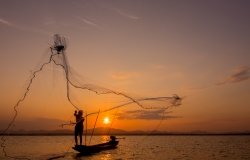 Silhouette of fisherman throwing net on the lake, Shutterstock