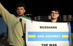 two protestors hold up a sign reading "Russians are against the war"