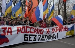 Boris Nemtsov stands at a protest holding a banner reading "For Russia and Ukraine Without Putin" in 2014.