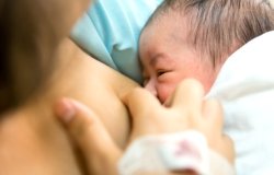 Young mother breastfeeding her newborn child in hospital after cesarean