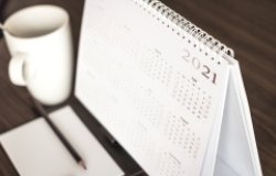 A coffee mug sits next to a desk calendar that shows the year 2021