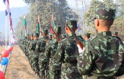 A line of men in camouflage face away from the camera.