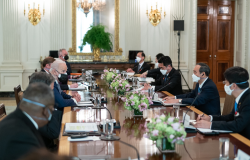 A group of men including President Biden and PM Suga sit around a conference table