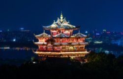 An ancient temple is lit up in front of a modern city skyline.