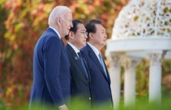President Biden, Prime Minister Kishida, and President Yoon standing together outside looking off camera.