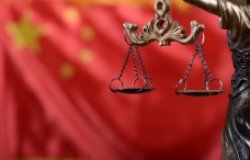 A statue of Justice with balanced scales and a Chinese flag in the background.