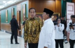 Two men are talking while photographers look on.