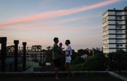 Husband, wife, and baby on balcony overlooking city 