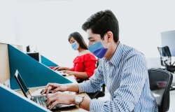 Workers with face masks at computers.