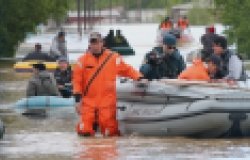 Man walking in knee-high water pulling a raft with people in it