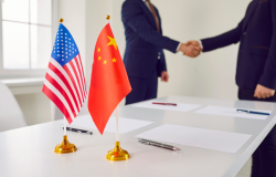American and Chinese Flags with two people shaking hands in the background