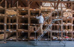 A man chooses wood from stacks of lumber