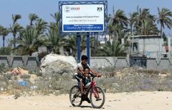 TWO BOYS ride a bike past a USAID sign last week announcing a desalination plant project in the Gaza Strip.