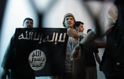 n this April 23, 2013 file photo, a suspected Yemeni al-Qaida militant, center, holds a banner as he stands behind bars during a court hearing in state security court in Sanaa, Yemen