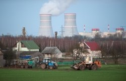 tractors work against the backdrop of a nuclear power plant