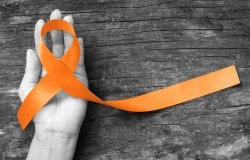Orange ribbon in hand for raising awareness of multiple sclerosis