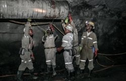 Underground platinum miners fitting a ventilation pipe