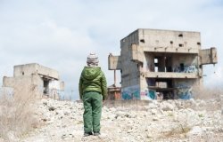 image of young boy looking over a bombed-out building 