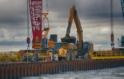 Construction of offshore section of gas pipeline on bottom of Baltic sea Nord stream-2. Pier goes into Narva Bay, excavator aligns bottom under bed of gas pipeline. Auxiliary vessels at sea.