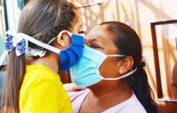 Mother and child touch noses while wearing face masks.