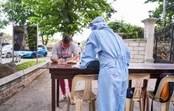 For contact tracing purposes, a churchgoer writes her contact details on a sheet of paper before she can proceed to the church’s entrance in Imus City, Philippines