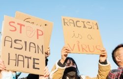 Signs of protestors, "Stop Asian Hate" and "Racism is a Virus"