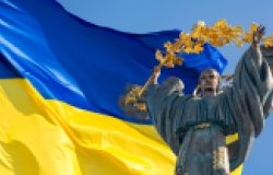 Monument of Independence of Ukraine in front of the Ukrainian flag. The monument is located in the center of Kyiv on Independence Square.