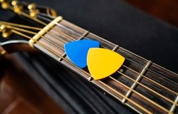 Blue and yellow guitar picks on an acoustic guitar