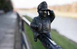 Small metal statue sitting on a fence 