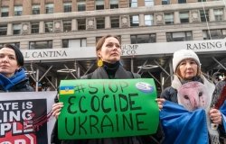 Woman holding sign with "Stop Ecocide Ukraine" written on it 