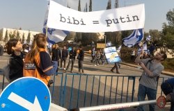 Protesters carrying sign comparing Netanyahu and Putin