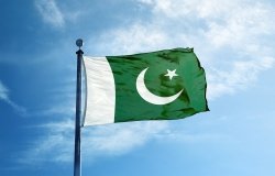 Pakistan flag against blue sky with some white clouds