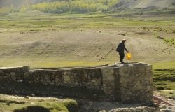 Man walks 4 miles to draw clean water from a pump above a mountain stream in Warduj, Afghanistan.