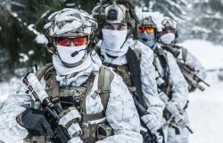 Action in cold conditions. Squad of soldiers with weapons in forest somewhere above the Arctic Circle